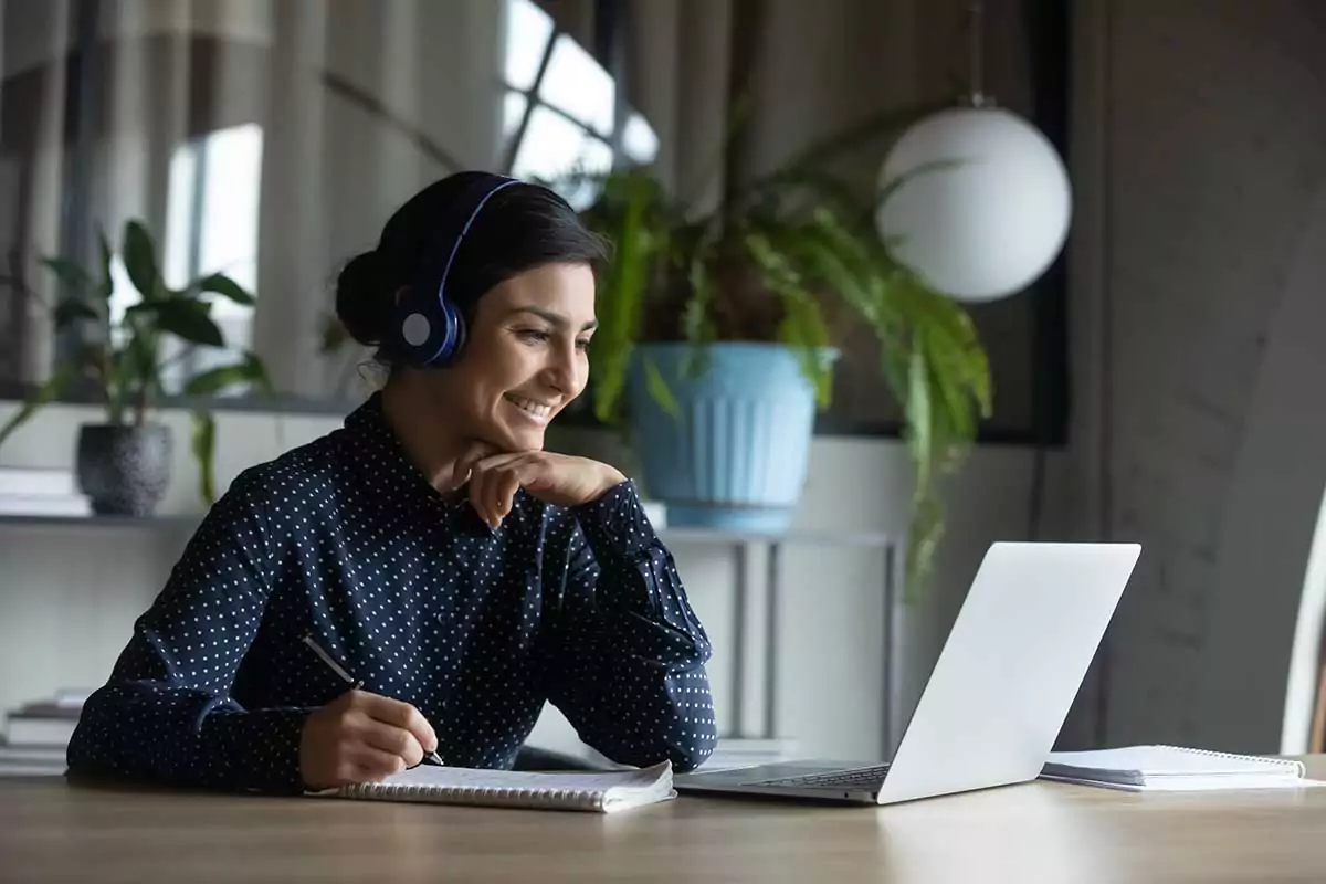 Motivierte Lehrerin der NELA Sprachschule schaut lächelnd auf Ihr Laptop