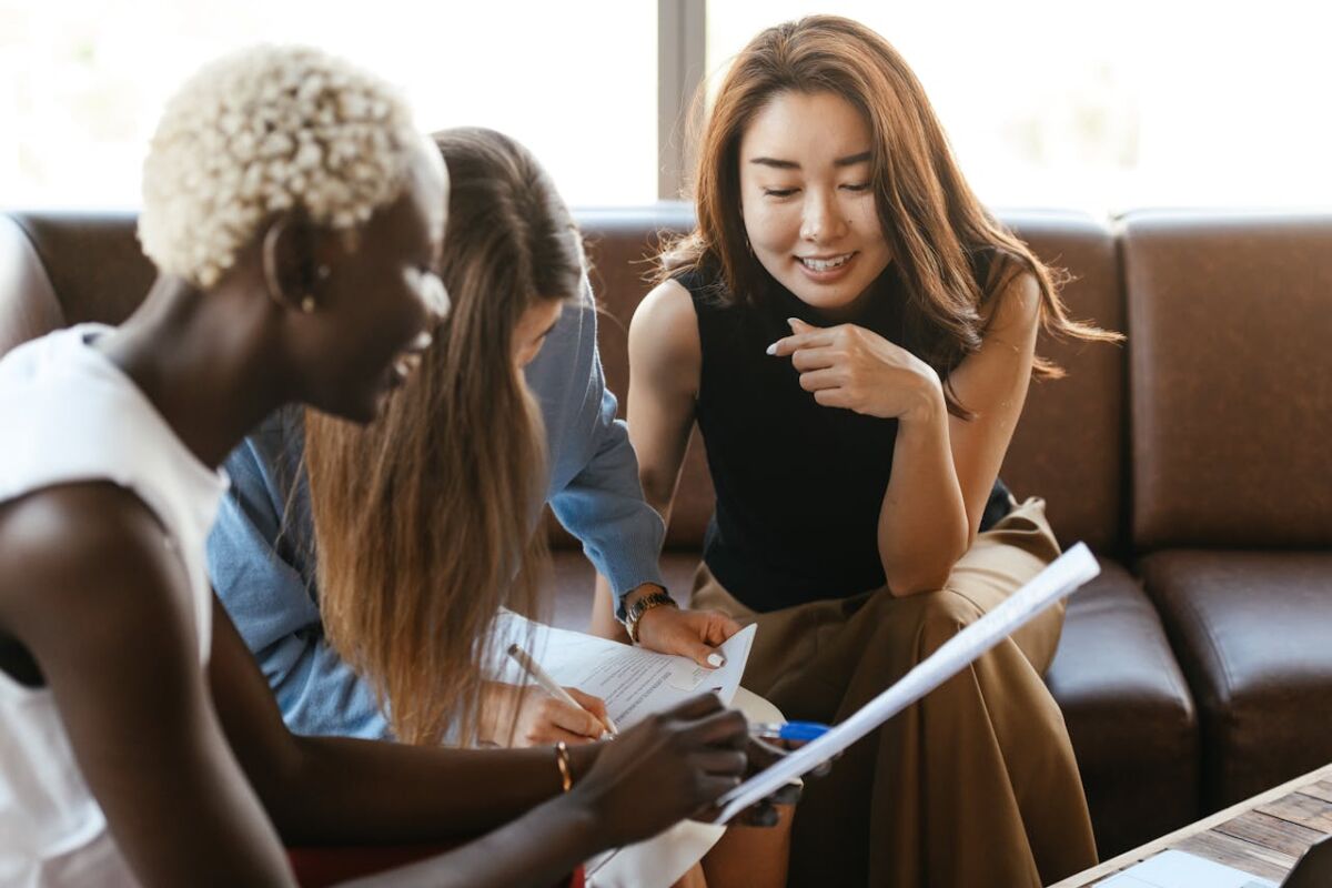 three women engaging in small talk while working with documents